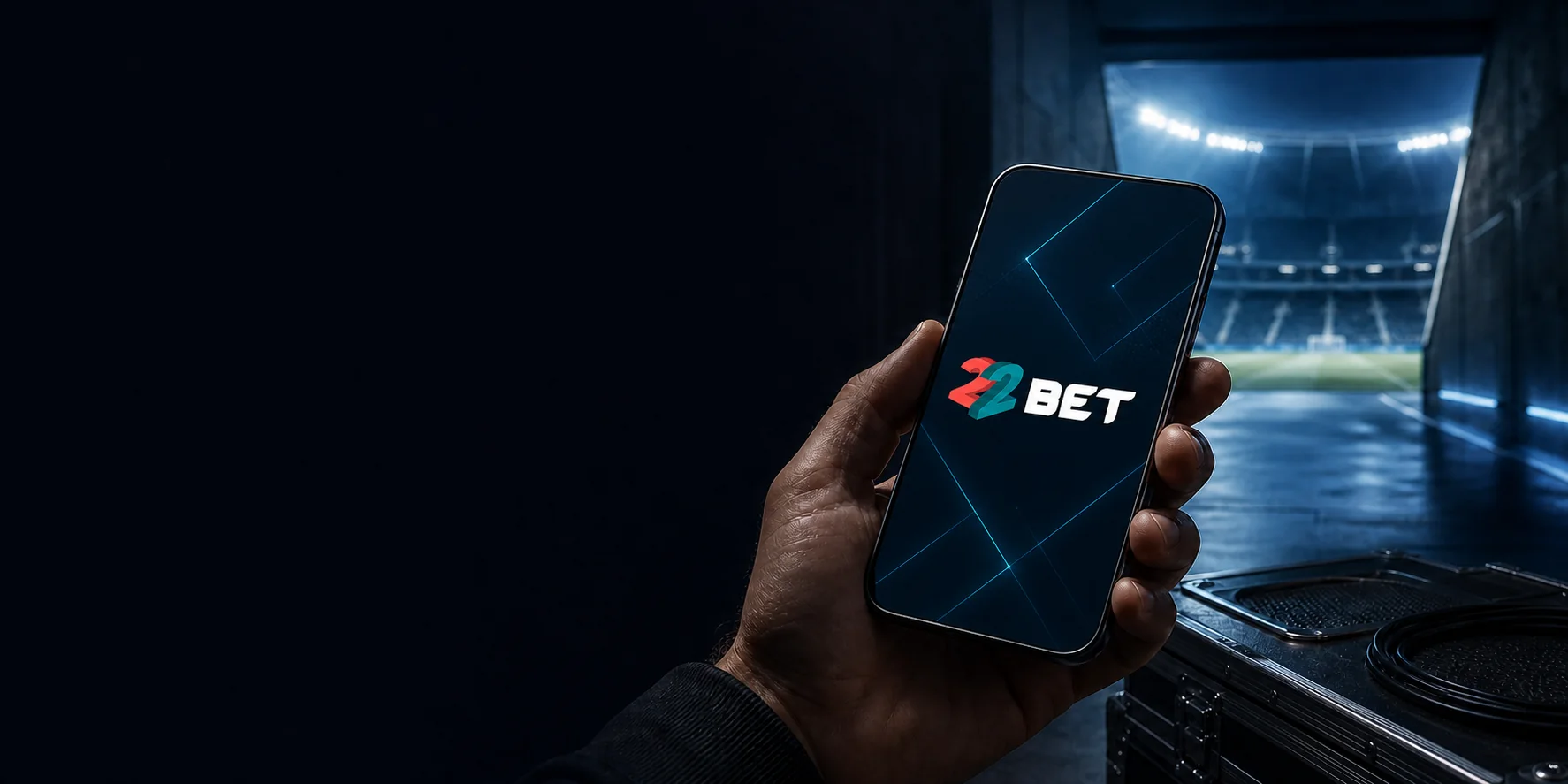 Teléfono con la aplicación de 22BET frente al túnel de un estadio