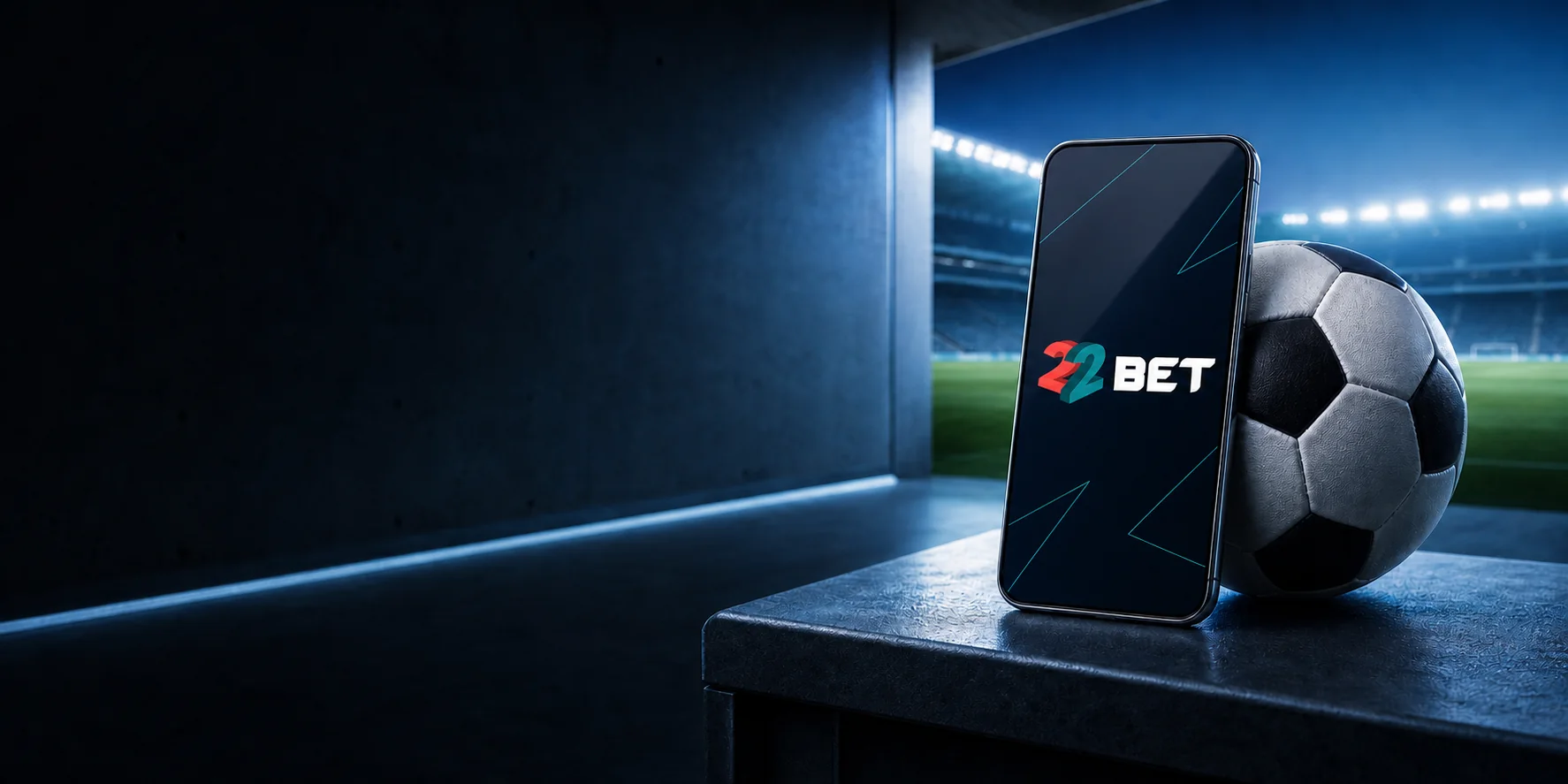 Teléfono con la aplicación de 22BET junto a un balón en un túnel de estadio